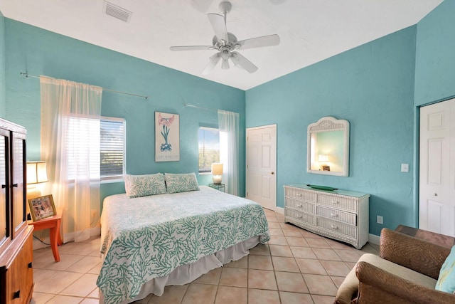 bedroom with light tile patterned floors, a closet, visible vents, ceiling fan, and baseboards