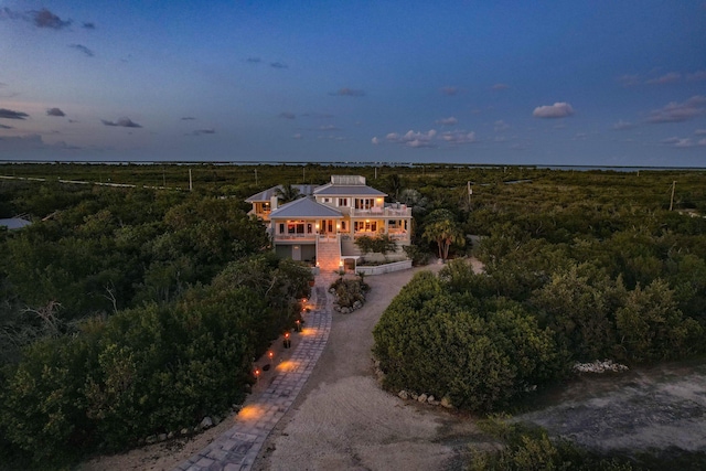 aerial view at dusk featuring a wooded view