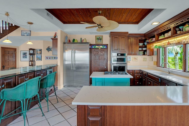 kitchen with a tray ceiling, light tile patterned floors, stainless steel appliances, wood ceiling, and a sink