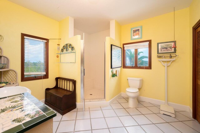 full bath featuring toilet, a shower stall, baseboards, and tile patterned flooring