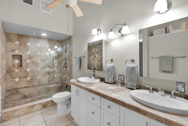 bathroom featuring a tile shower, vanity, ceiling fan, toilet, and tile patterned floors