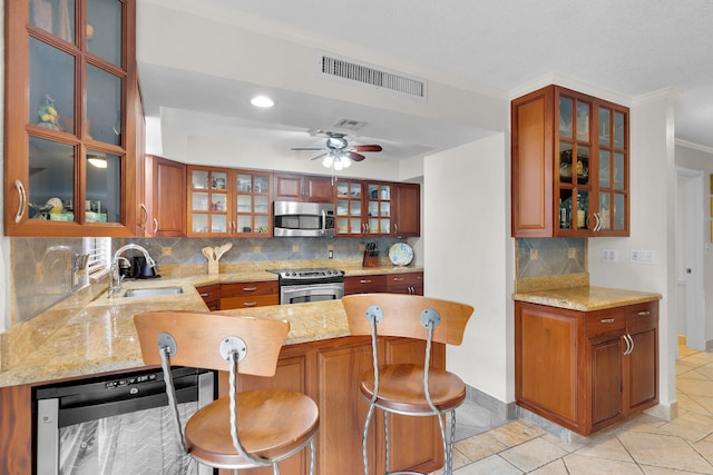 kitchen featuring sink, tasteful backsplash, appliances with stainless steel finishes, a kitchen breakfast bar, and kitchen peninsula