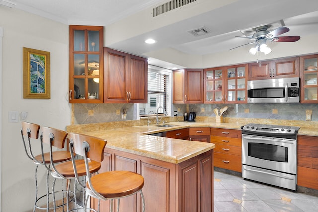 kitchen featuring sink, appliances with stainless steel finishes, a kitchen breakfast bar, kitchen peninsula, and decorative backsplash