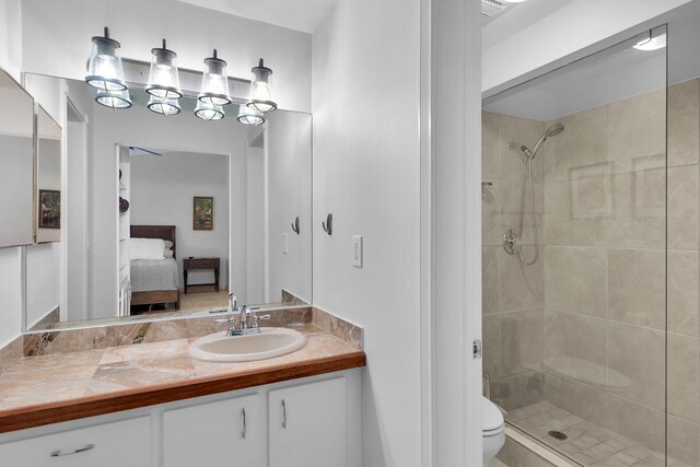 bathroom with a tile shower, vanity, and toilet