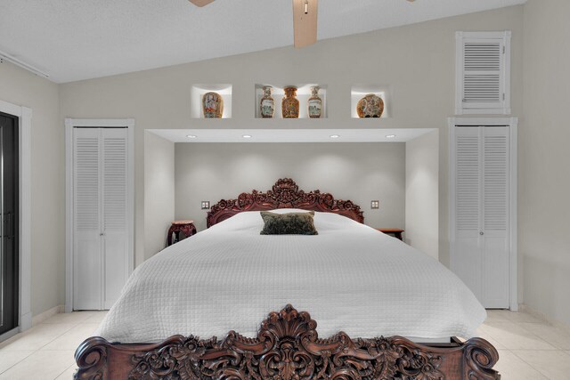 bedroom featuring ceiling fan, lofted ceiling, a closet, and light tile patterned floors