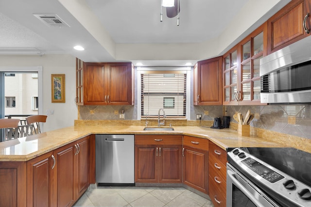 kitchen with sink, light tile patterned floors, a breakfast bar, stainless steel appliances, and kitchen peninsula