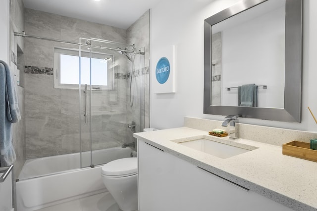 full bathroom featuring enclosed tub / shower combo, vanity, and toilet