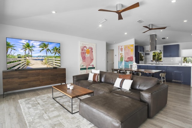 living room featuring ceiling fan, lofted ceiling, and light wood-type flooring