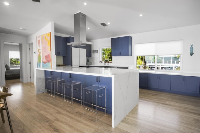 kitchen featuring island range hood, light hardwood / wood-style flooring, blue cabinetry, and a wealth of natural light