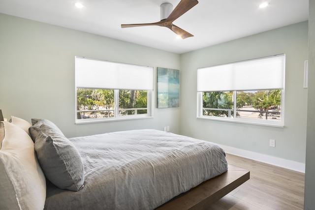 bedroom with hardwood / wood-style flooring, ceiling fan, and multiple windows