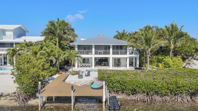 rear view of house featuring a patio area, a sunroom, and a water view