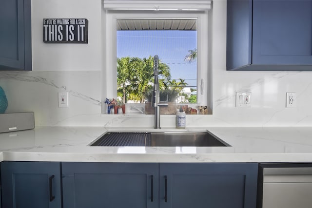 kitchen featuring sink, light stone countertops, and blue cabinets