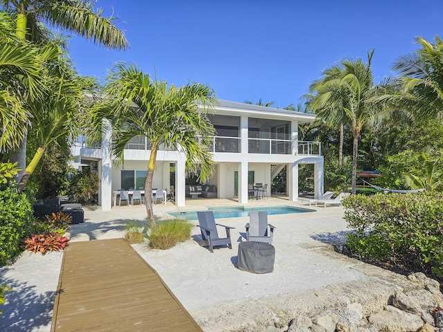 rear view of property featuring a balcony, a sunroom, and a patio area