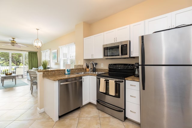 kitchen with appliances with stainless steel finishes, decorative light fixtures, white cabinets, dark stone counters, and kitchen peninsula