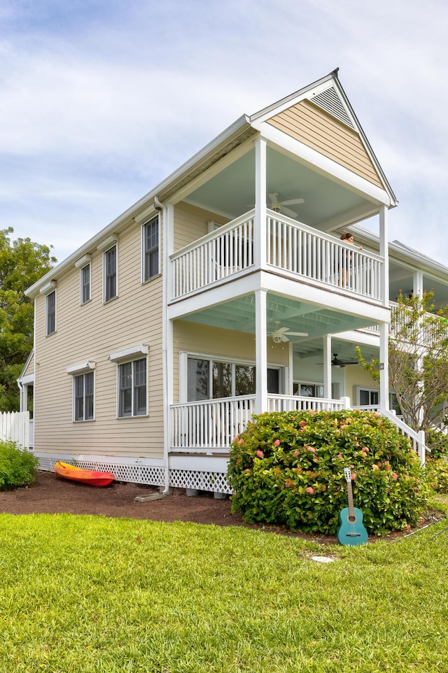 rear view of house with a yard, a balcony, and ceiling fan