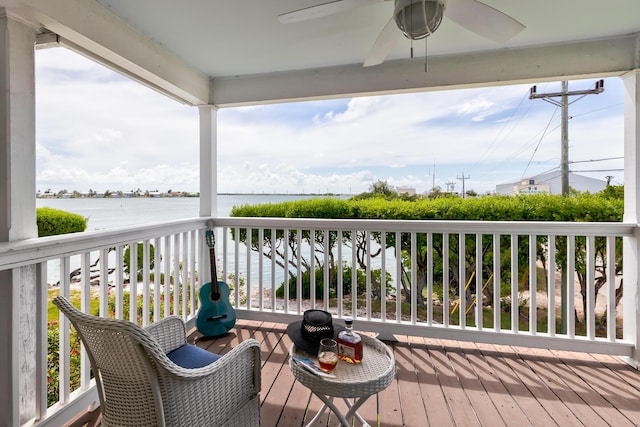 wooden terrace with a water view and ceiling fan