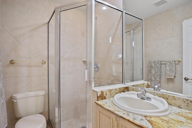 bathroom featuring vanity, tile walls, toilet, and walk in shower