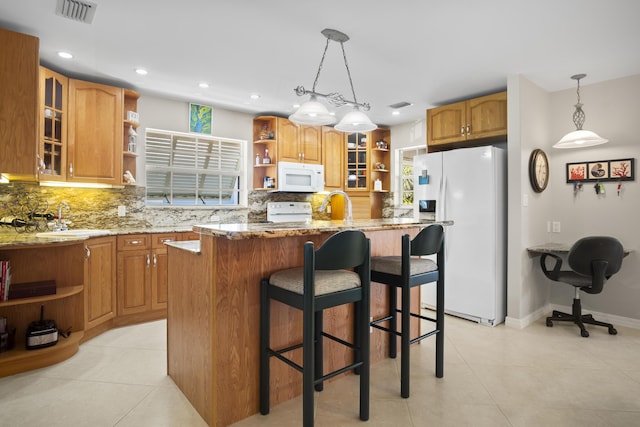 kitchen with a kitchen island, pendant lighting, sink, light stone countertops, and white appliances