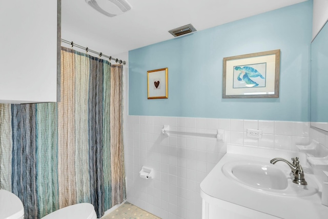 bathroom with tile walls, vanity, curtained shower, and toilet