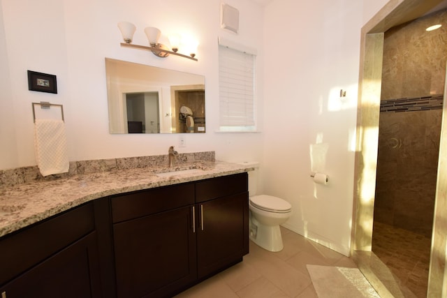 bathroom with tiled shower, vanity, toilet, and tile patterned flooring