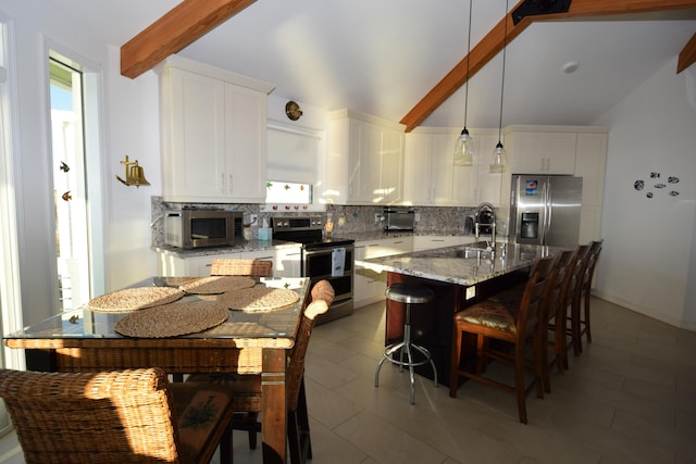 kitchen featuring hanging light fixtures, stainless steel appliances, white cabinets, and a center island with sink