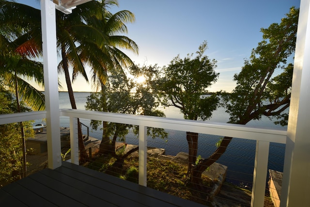 deck at dusk featuring a water view