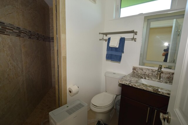 bathroom featuring tiled shower, vanity, and toilet