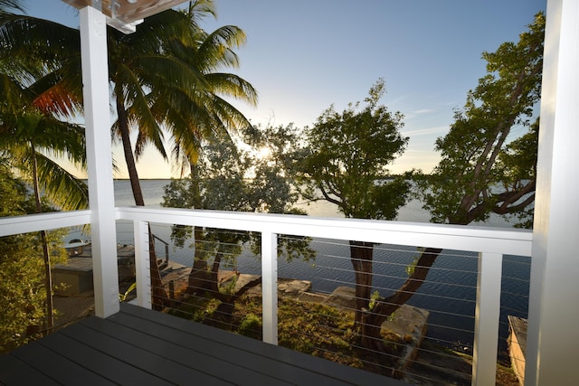 deck at dusk featuring a water view