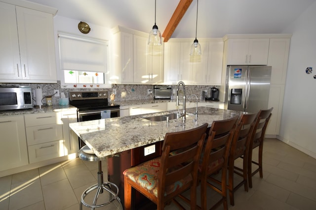 kitchen with sink, a breakfast bar, appliances with stainless steel finishes, a center island with sink, and decorative backsplash