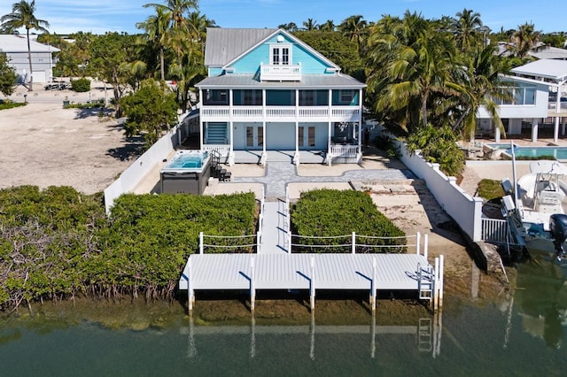 back of house with a water view, a balcony, a jacuzzi, and a patio area