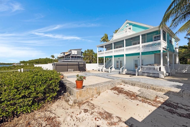 rear view of property with a jacuzzi, a sunroom, and a patio