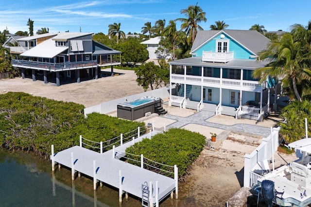 rear view of property featuring a water view, a balcony, a hot tub, and a patio