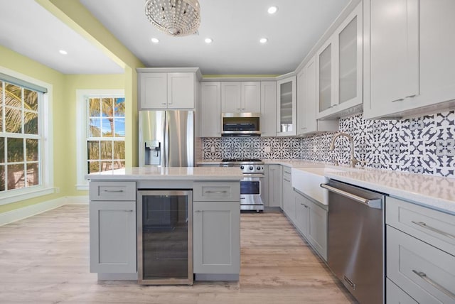 kitchen featuring sink, light hardwood / wood-style flooring, appliances with stainless steel finishes, beverage cooler, and backsplash