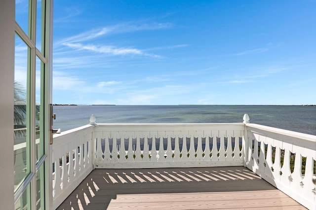 wooden terrace featuring a water view and a view of the beach