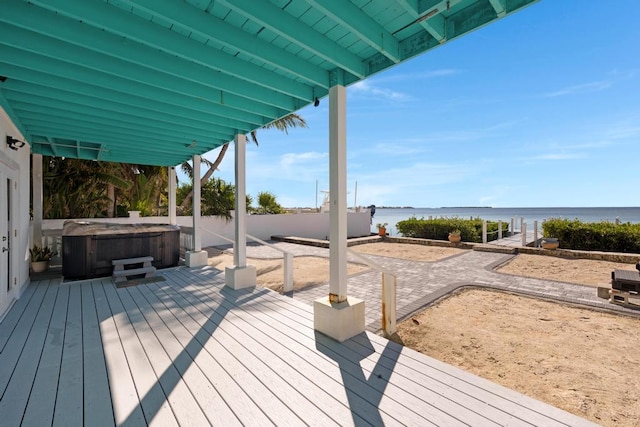 wooden deck featuring a hot tub and a water view