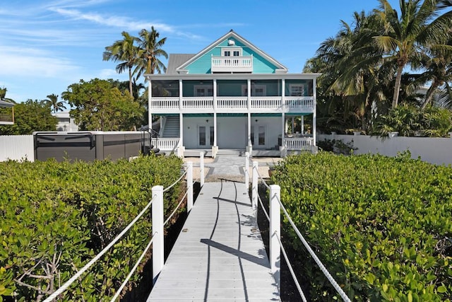 rear view of property featuring a hot tub, a sunroom, and a patio area