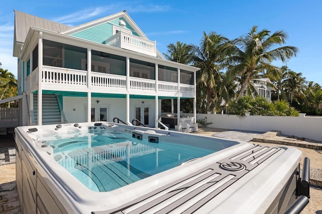 back of house with a hot tub, french doors, and a sunroom