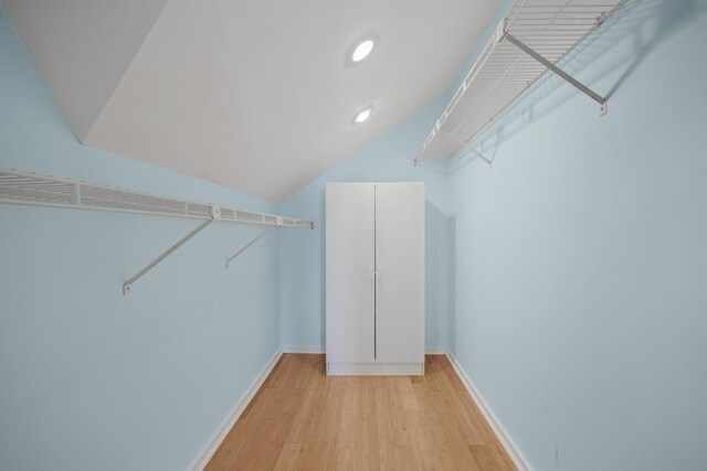 walk in closet with light hardwood / wood-style flooring and vaulted ceiling