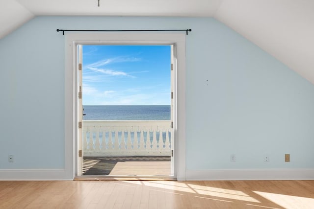 additional living space with hardwood / wood-style flooring, a water view, a beach view, and lofted ceiling