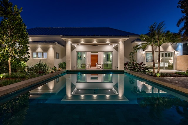 pool at twilight featuring ceiling fan, an outdoor pool, and a patio