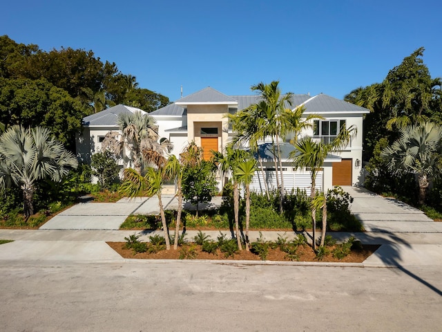 view of front of home with a garage, concrete driveway, and stucco siding