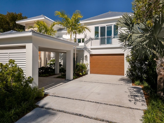 view of front of property featuring a garage, a balcony, concrete driveway, and stucco siding