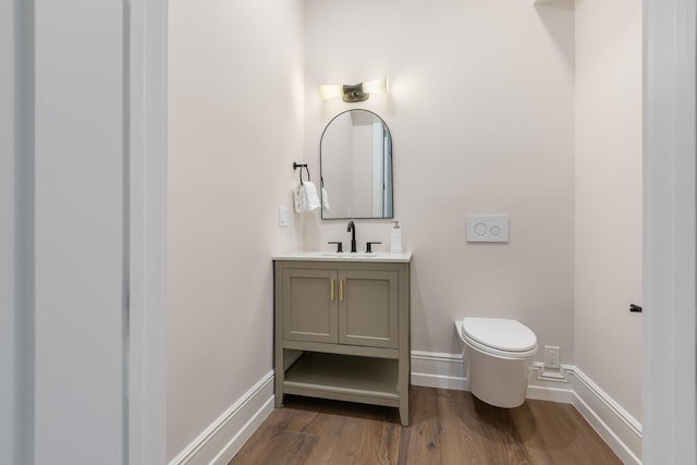 bathroom with toilet, wood finished floors, vanity, and baseboards