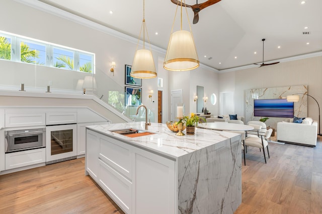 kitchen with beverage cooler, light wood finished floors, open floor plan, and a sink