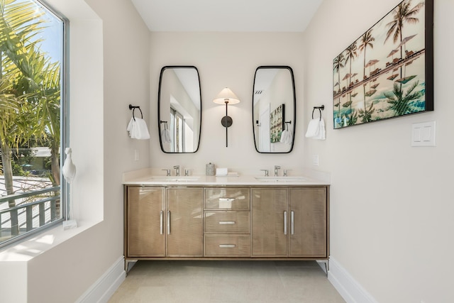 bathroom with a sink, baseboards, and double vanity