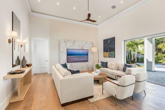 living area featuring visible vents, a towering ceiling, crown molding, light wood-style floors, and recessed lighting