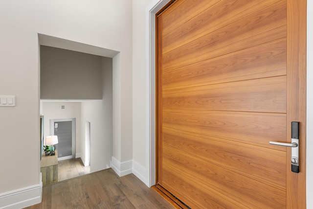 hallway featuring dark wood-type flooring and baseboards