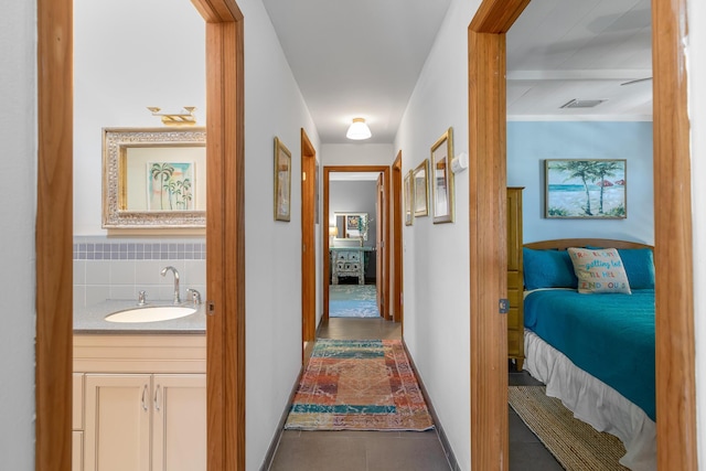 corridor with sink and dark tile patterned floors