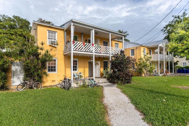 view of front of home with cooling unit, a front lawn, and a balcony