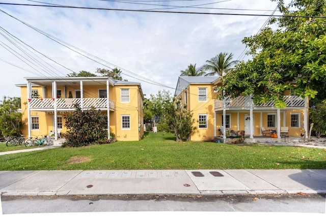 view of front of home with a front yard, a balcony, and covered porch